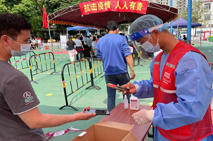 何贞（右）在联富社区濠三小区核酸检测点参加志愿服务